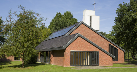 Modernes Kirchengebäude aus Backstein umgeben von Bäumen