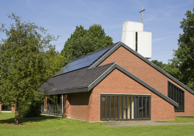 Modernes Kirchengebäude aus Backstein umgeben von Bäumen