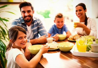 Das Foto zeigt eine fröhliche Familie beim gemeinsamen Frühstück