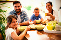 Das Foto zeigt eine fröhliche Familie beim gemeinsamen Frühstück
