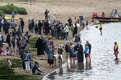 Das Foto zeigt ein Tauffest am Weserstrand in Bremen. Die Taufgäste stehen am Strand und im Wasser.