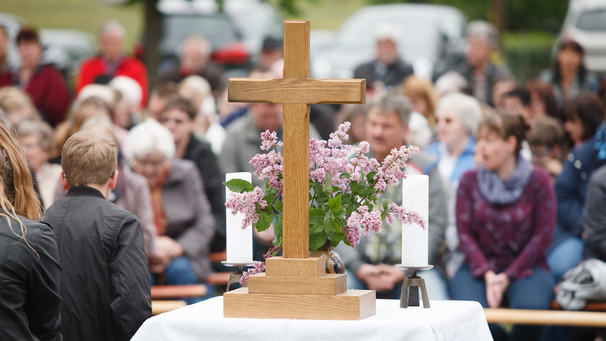Gottesdienst draussen, ein Holzkreuz steht auf dem Altar