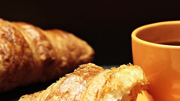 Das Foto zeigt Croissants und eine Tasse Kaffee