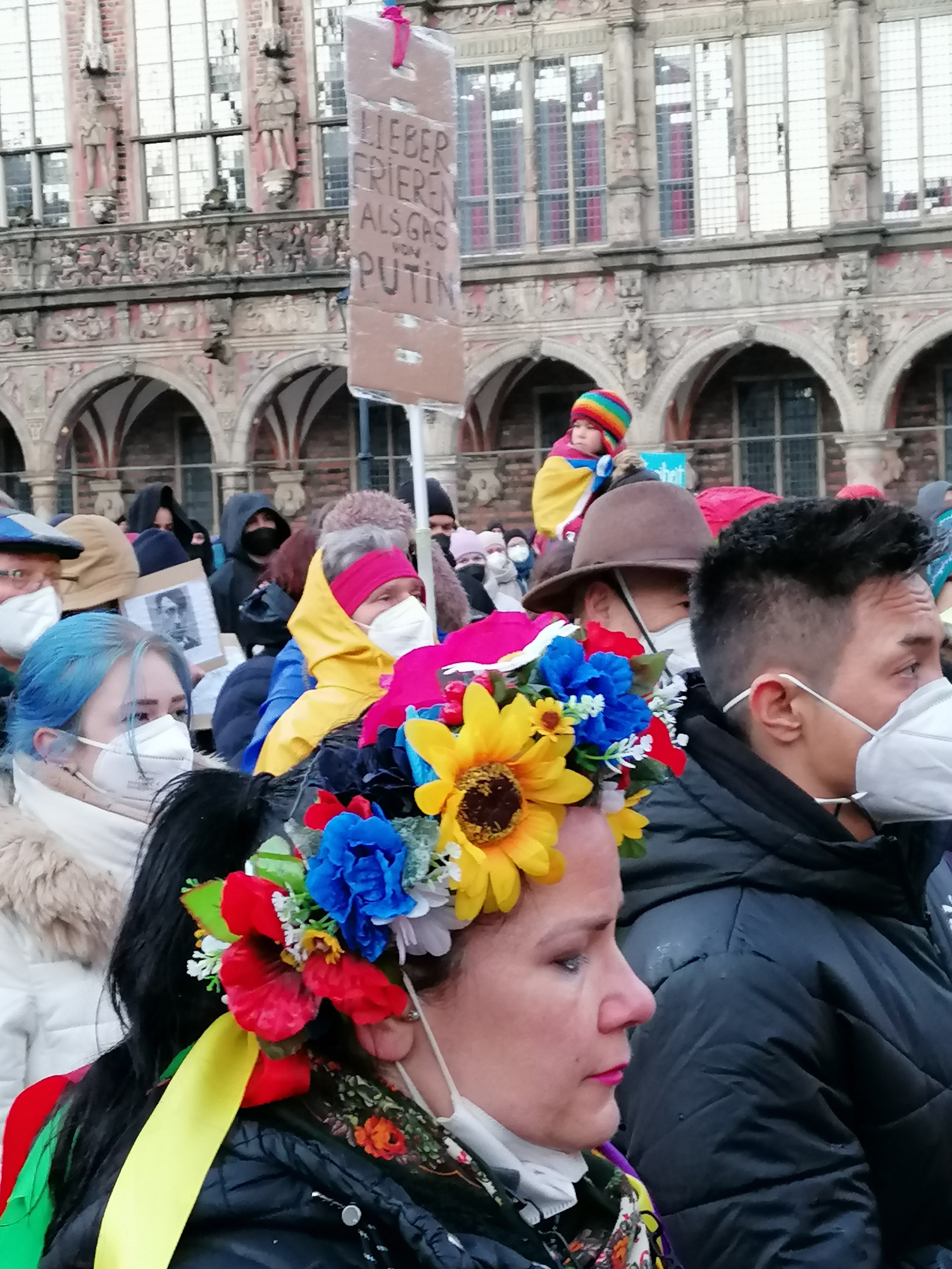 Das Foto zeigt eine Frau aus der Ukraine in traditioneller Tracht mit einem bunten Bluemnkrank auf dem Kopf. Sie nimmt an der Demonstration auf dem Bremer Marktplatz aus Anlass des russischen Überfalls auf die Ukraine teil.