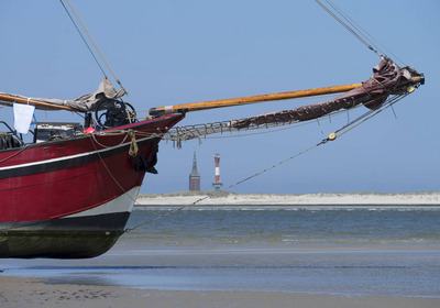 Die Verandering liegt bei Ebbe im Wattenmeer. Im Hintergrund ist ein Küstenstreifen mit Leuchtturm zu sehen.