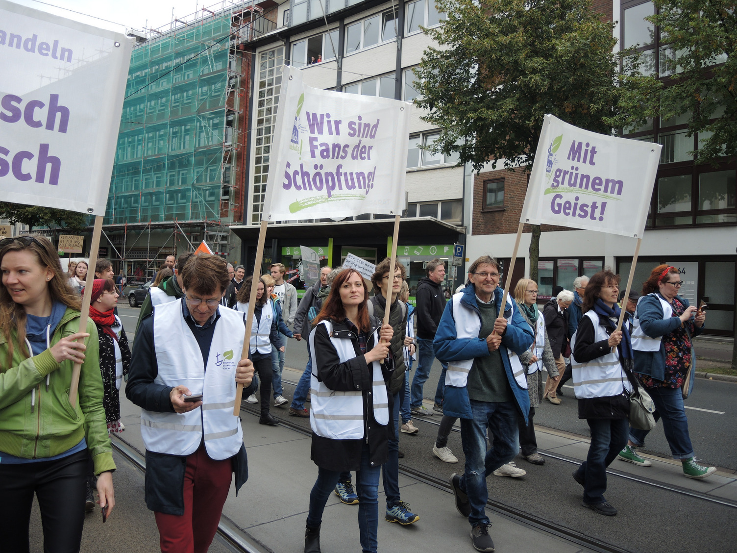 Menschen demonstieren für den Klimaschutz und halten Transparente hoch  mit Mitarbeitenden der Bremischen Evangelischen Kirche.