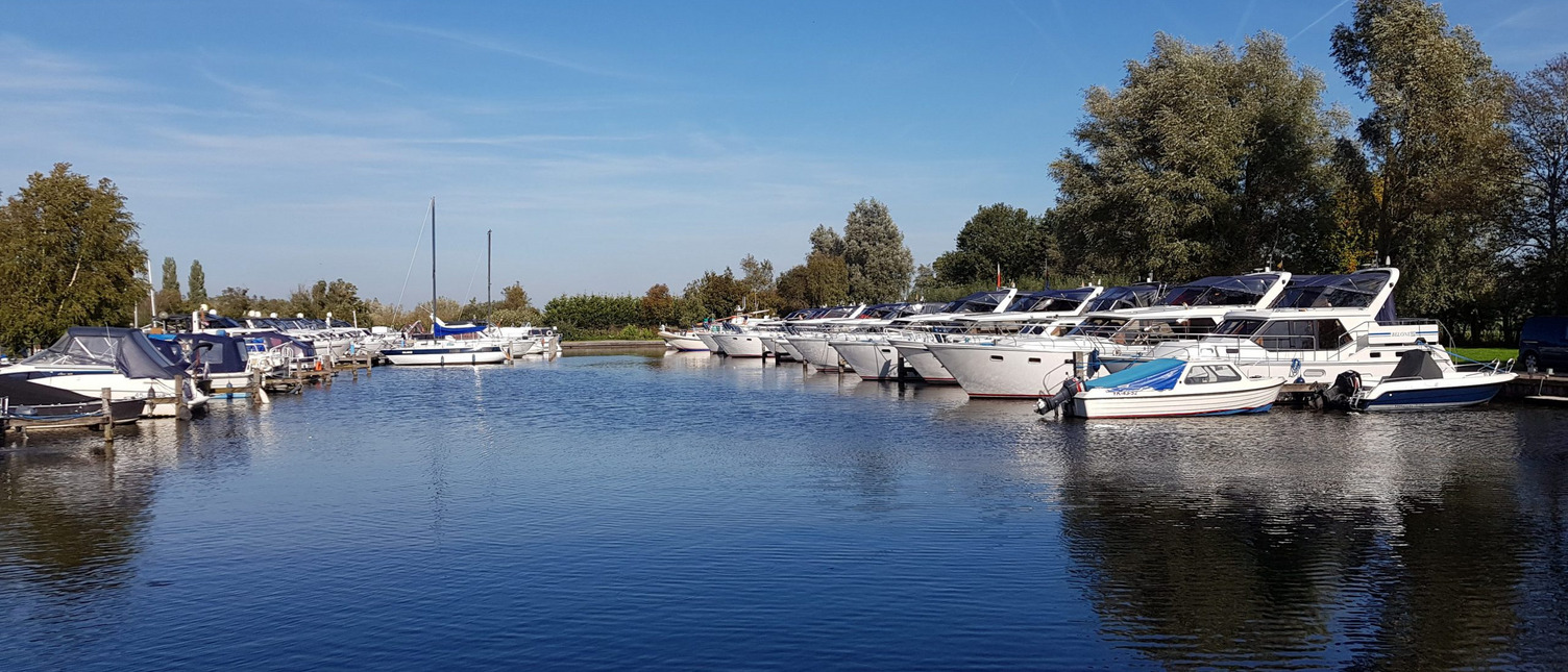 Ein weiter Blick über den Hafen von Langelille, in dem viele ähnlich aussehenden Boote liegen.