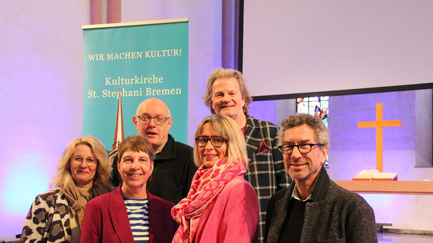 Sechs Personen stehen vor einem Altar