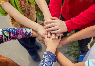 Viele Kinder legen ihre Hände aufeinander.