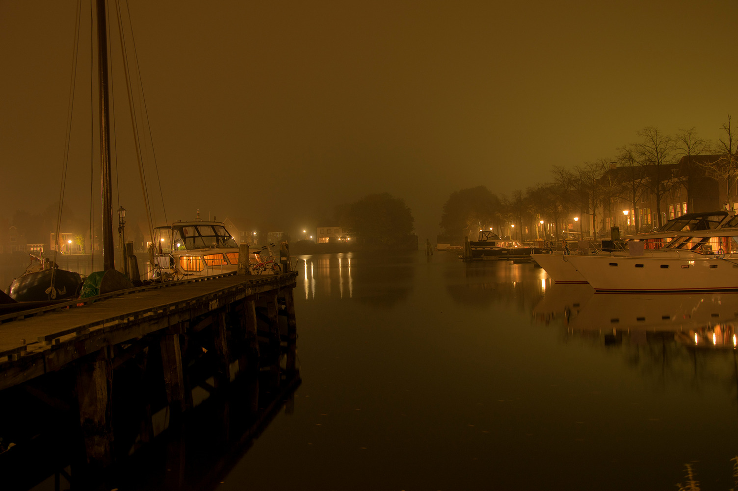Ein Foto vom Hafen in Blokzijl bei Nacht. Es ist neblig und der Hafen ist von Lichtern gezäumt.