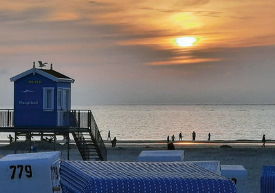 DLRG-Station am Strand mit Strandkörben und untergehender Sonne