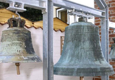 Das Bild zeigt drei historische Glocken aus dem 18. Jahrhundert im Innenhof eines Lübecker Museums