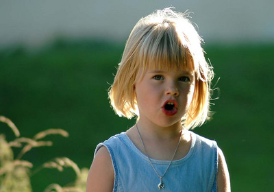Das Foto zeigt ein singendes kleines Mädchen mit blonden Haaren und einem blauen T-Shirt