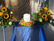 Innenansicht der Kapelle. Ein Altar mit großer Kerze. Daneben viele bunten Blumen. 