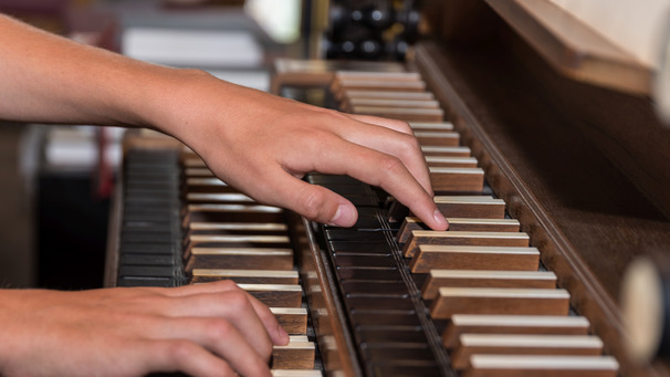 Hände spielen auf der Tastatur einer Orgel