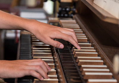 Hände spielen auf der Tastatur einer Orgel