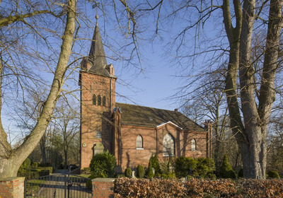Kirchgebäude umgeben von einem Friedhof und Bäumen