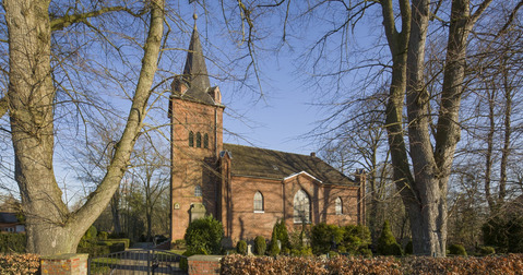 Kirchgebäude umgeben von einem Friedhof und Bäumen