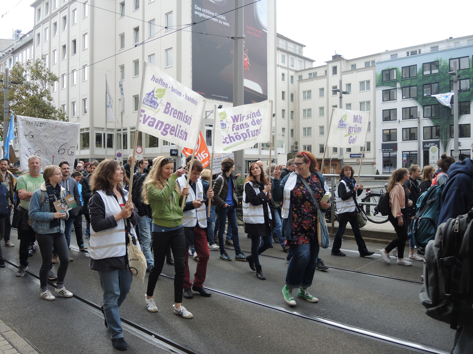 Menschen demonstieren für den Klimaschutz und halten Transparente hoch mit Mitarbeitenden der Bremischen Evangelischen Kirche.