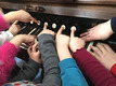 Das Foto zeigt von oben acht Kinderhände an einer Orgeltastatur, die auf die Tasten drücken