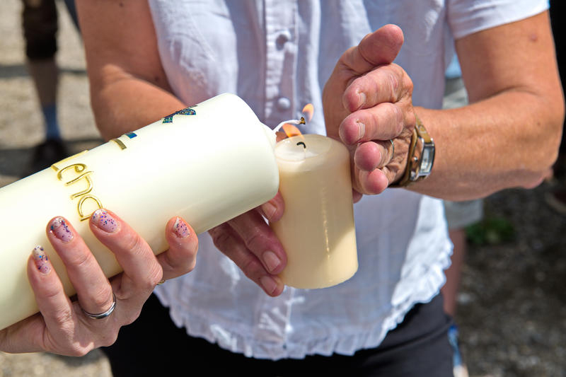 Auf dem Foto sieht man, wie eine Taufkerze angezündet wird.