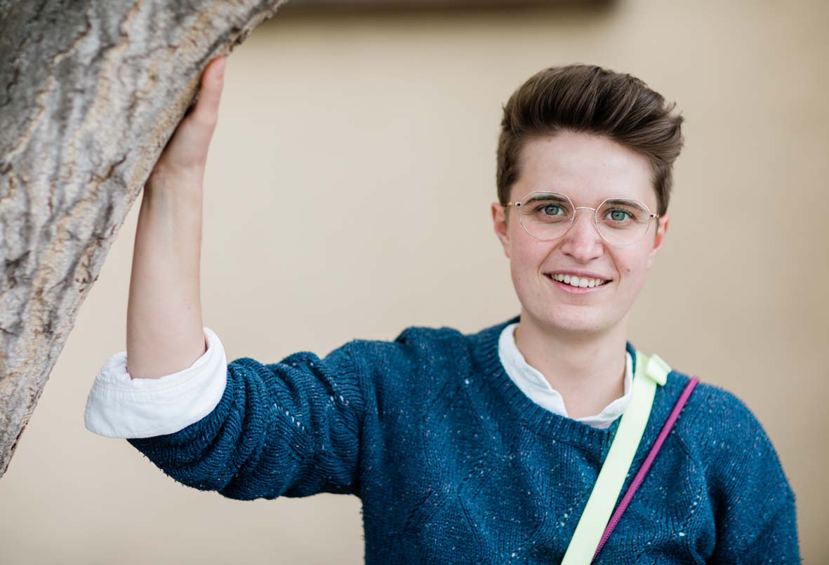 Das Foto zeigt die Synoden-Päses der EKD, Anna-Nicole Heinrich salopp an einen Baum gelehnt