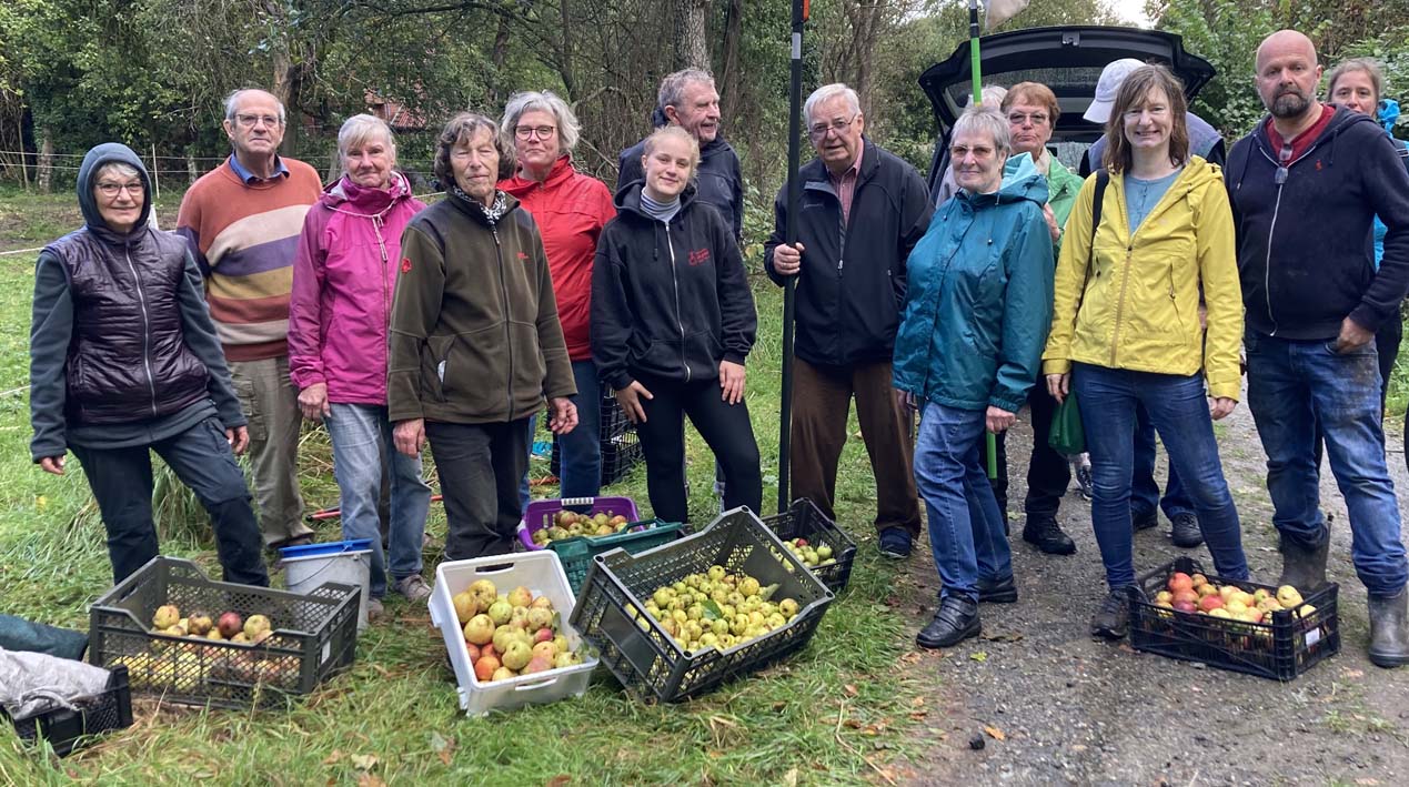 Das Foto zeigt eine Gruppe vonn Frauen und Männern, die Äpfel geerntet haben