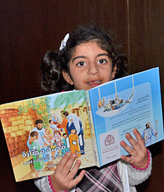 Ein Kind hält eine illustrierte Kinderbibel in den Händen.